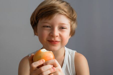 Very happy boy smiling and eating a ripe red Appleの写真素材
