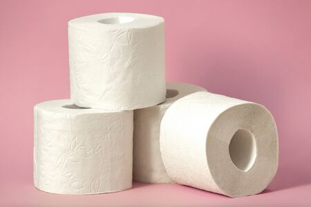 Four rolls of white toilet paper stand on a pink backgroundの写真素材