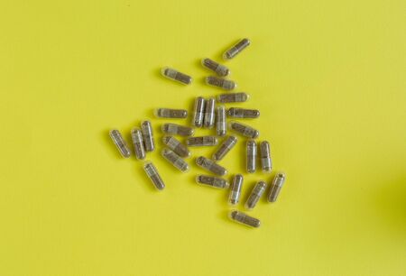 Medicinal capsules are scattered on a yellow background.の写真素材