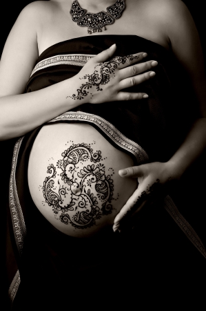 A black and white photo of henna tattoo paste on a woman s hands and pregnant belly  Henna application in the 8th month of pregnancy is believed to bring an easy birth and healthy child の写真素材