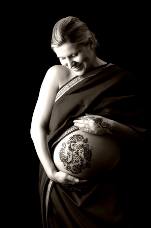 A black and white photo of henna tattoo paste on a woman s hands and pregnant belly  Henna application in the 8th month of pregnancy is an ancient practice believed to bring an easy birth and healthy child  の写真素材