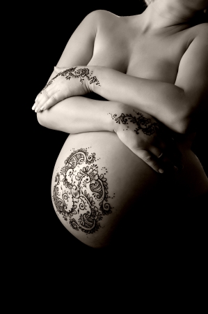A black and white photo of henna tattoo paste on a woman s hands and pregnant belly  Henna application in the 8th month of pregnancy is believed to bring an easy birth and healthy child  の写真素材