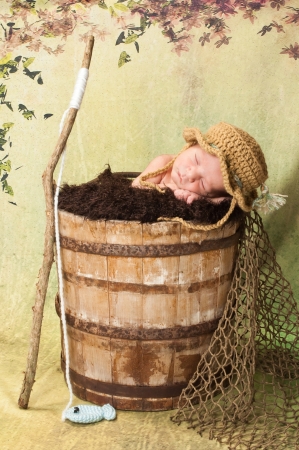 7 day old newborn baby boy sleeping in an old, weathered wooden bucketの写真素材