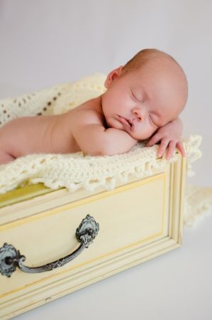 Newborn baby girl sleeping in a vintage yellow drawer の写真素材