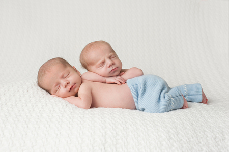 One month old fraternal, twin baby boys sleeping on a white blanket.の写真素材