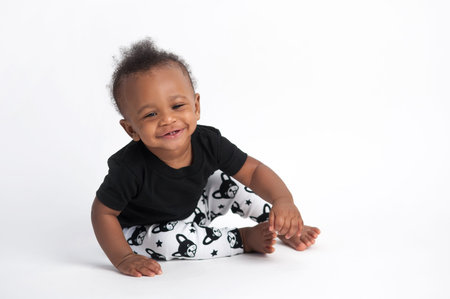 A smiling, nine month old, baby boy sitting on a white, seamless background.の写真素材