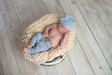 Six week old baby boy wearing light blue pjs and lying in a round, bucket.の写真素材
