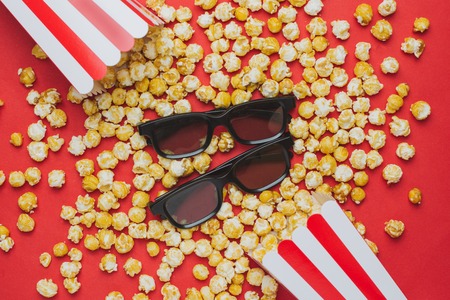 Glasses and popcorn on a red background top viewの写真素材