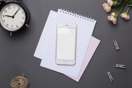 Phone with empty screen with paper,alarm clock and flowers on grey background in vintage styleの写真素材
