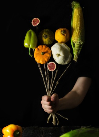 Autumnal vegetables zucchini and pumpkin with male hand on a black backgroundの写真素材