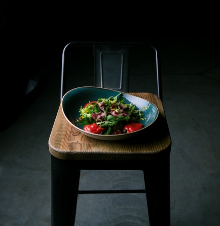 Meat salad with fresh herbs and dried tomatoes in a restaurantの写真素材