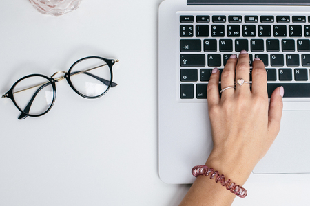 Female hands use laptop keyboard on white table top viewの写真素材