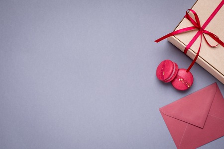 Gray background with gift envelopes , gift box and macaroons top viewの写真素材