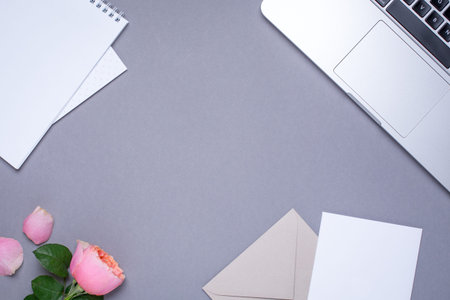 Gray wallpaper with gift card, pink rose and laptop top viewの写真素材