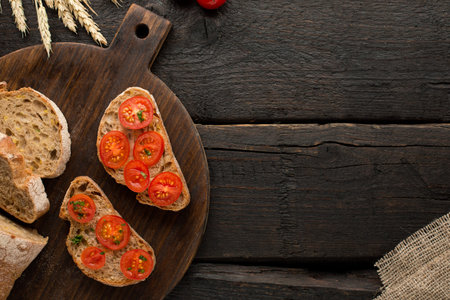 Wooden background with tomatoes toasts and bread on a board top view