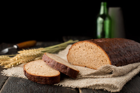 Fresh bread on sackcloth with wheat on a wooden background side view