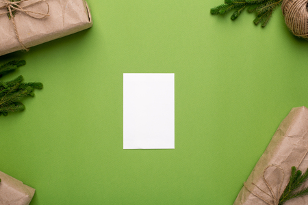 Present card and eco gifts with green plants in craft paper on a green background top vewの写真素材