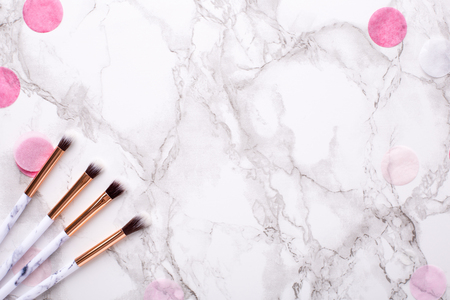 Cosmetic brushes with pink decorations on a marble background top viewの写真素材