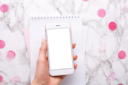 Female hand with a mobile phone in the office on the background of a marble table