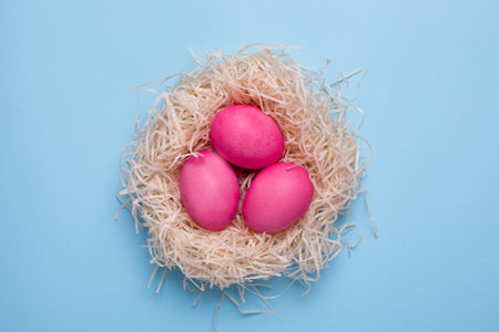 Easter pink eggs with watercolor brushstrokes on a blue background top view