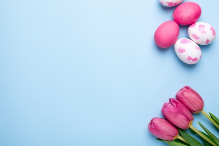 Pink flowers tulips and easter eggs on a blue background top viewの写真素材