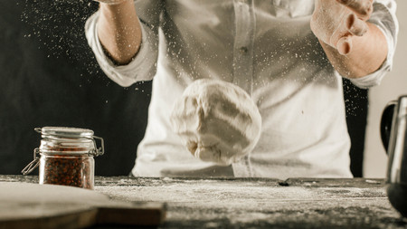 Male chef hands knead dough with flour on kitchen table side viewの写真素材