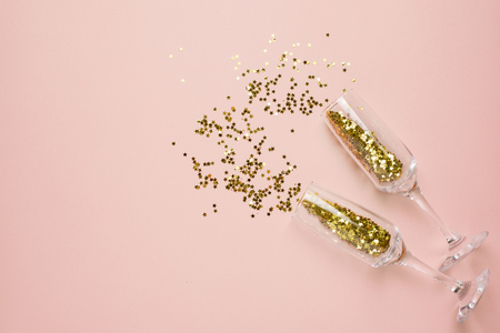 Champagne glasses with golden stars confetti on beige color paper background minimal styleの写真素材