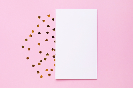 White gretting card with golden love confetti on pink color paper background minimal style top viewの写真素材