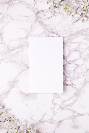 Empty card with white flowers on marble table top view and flat lay style.の写真素材
