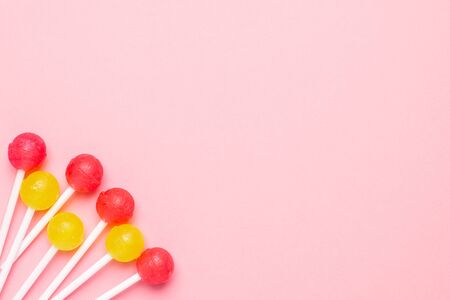 Pastel pink background with sweet pink and yellow candies. Minimalist composition top view.の写真素材