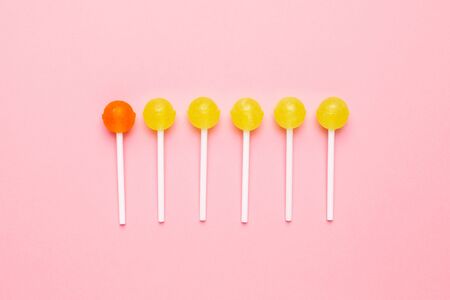 Sweet yellow and orange candy lolipop on pastel pink background. Minimalist composition top view.の写真素材