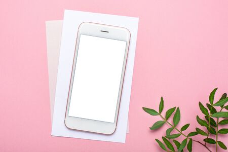 Mobile phone mock up and verdure on pink pastel table in flat lay style. Woman working desk top view. Summer colourの写真素材