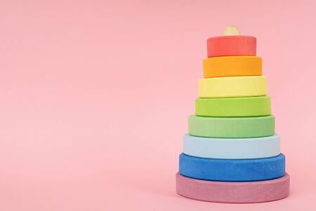 Children's wooden multi-colored pyramid on a pink background side viewの写真素材