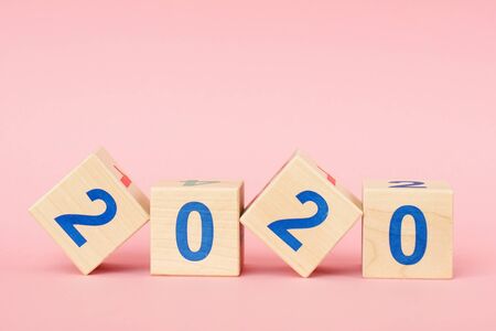 Wooden block cube with number New year 2020 on pink backgroundの写真素材