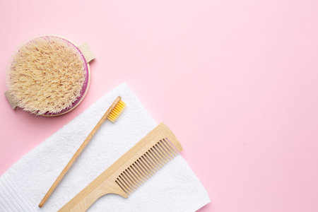 Eco wooden toothbrush , comb and brush for dry massage on pink background with copyspace , bathroom...