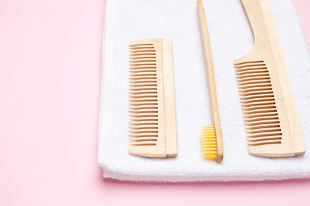 Eco wooden toothbrush , comb and white bath towel on pink background , bathroom and spa accessory...