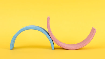 Colorful Waldorf wooden rainbow on yellow background side view, montessori teaching pedagogy