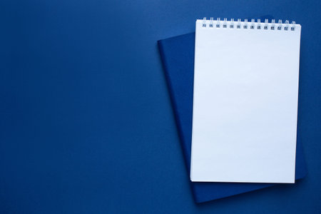 White and blue office notebook on a classic blue background with copyspace. Trendy color 2020
