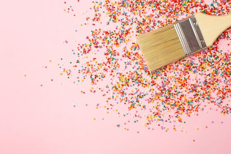 Brush and multicolored round confetti topping for sweets, colorful macro background. Tasty sweets and desserts concept top viewの写真素材