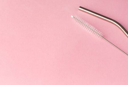 Metal, bendy drinking straw and steel cleaning brush on pink background. Aluminum stainless reusable bar equipment for drink alcohol cocktails, water or lemonade. Eco friendly alternativeの写真素材