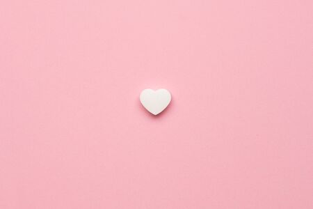 White little heart like on pink background. Minimalistic background for holidays top view.の写真素材