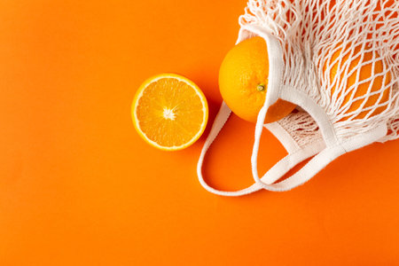 Oranges in cotton shopping eco friendly bag on orange background with copyspace, fruit flatlay,...