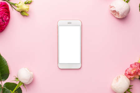 Mobile phone and Ranunculi pink flower bouquet on pink background with copyspaceの写真素材