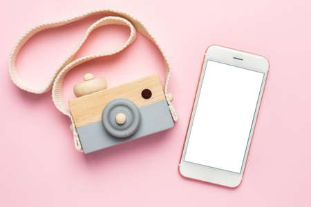 Mobile phone and wooden baby toy camera on pink background , natural eco materials and early baby developmentの写真素材