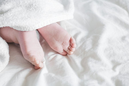 Newborn toddler boy legs with towel on bed top viewの写真素材