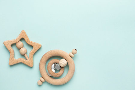 Wooden baby toy rattle on light blue background, natural eco materials and early baby development...