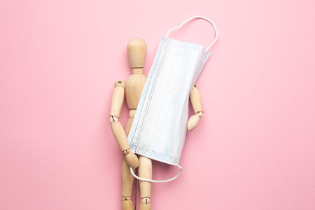Wooden man with medical mask, second wave, protection from the covid virus