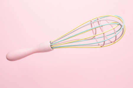 Multi-colored pastel kitchen whisk on pink background, cute kitchen utensils, feminine cookingの写真素材