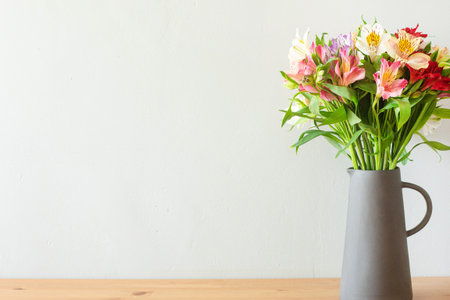 Colorful flowers in a cement vase on a wooden table with copyspace side viewの写真素材