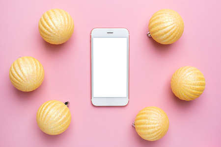 Mobile phone and Shiny gold balls on a pink background, Christmas decorations and mobile screen top viewの写真素材